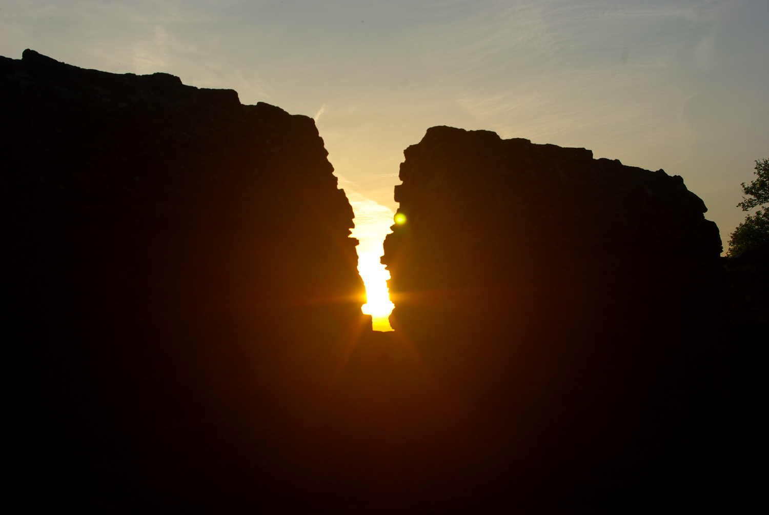 Die Sonne scheint zwischen Burgzinnen hindurch