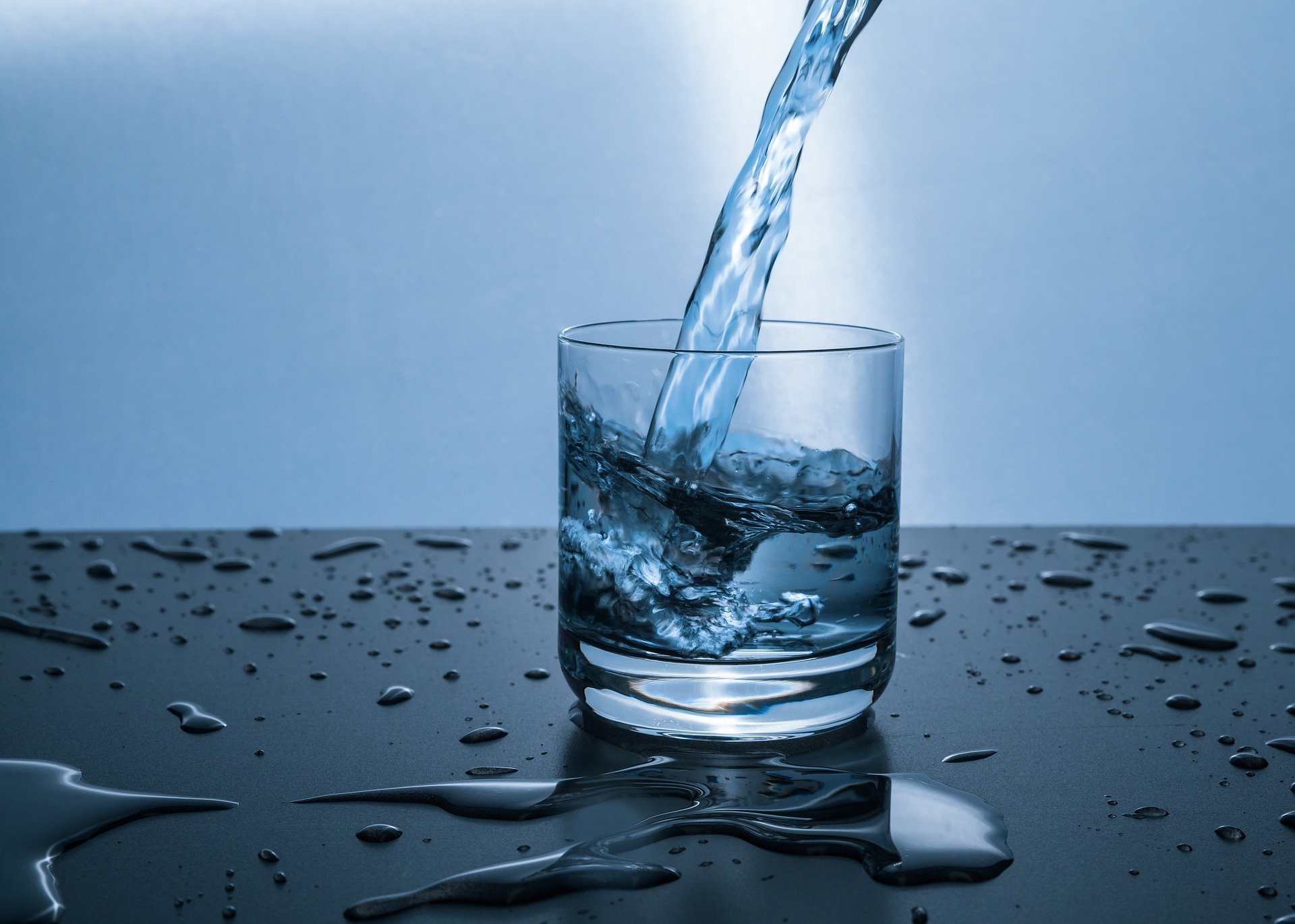 Ein Glas wird schwungvoll mit Wasser gefüllt.