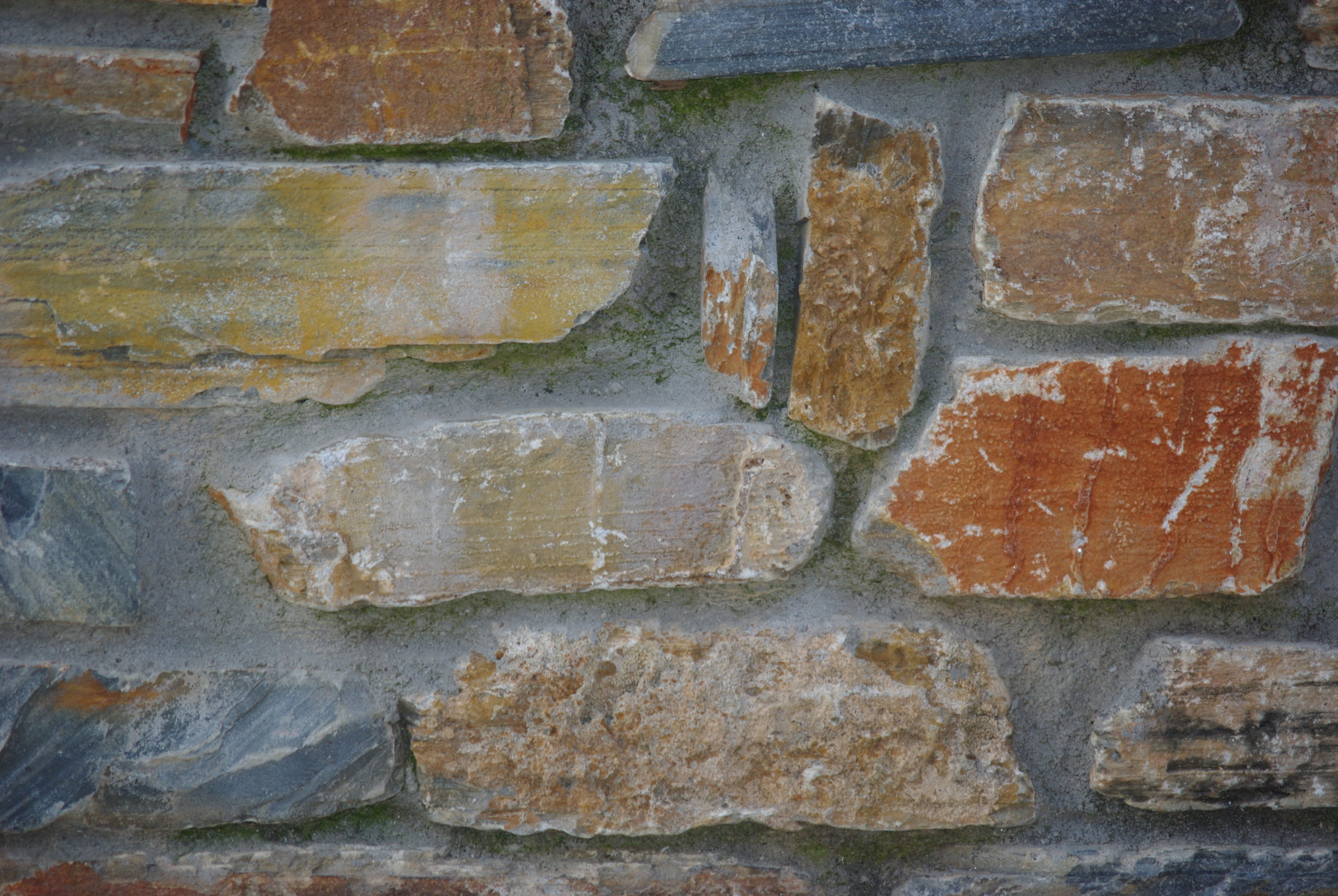 Eine Mauer aus verschiedenfarbigen Ziegelsteinen und Bruchstücken