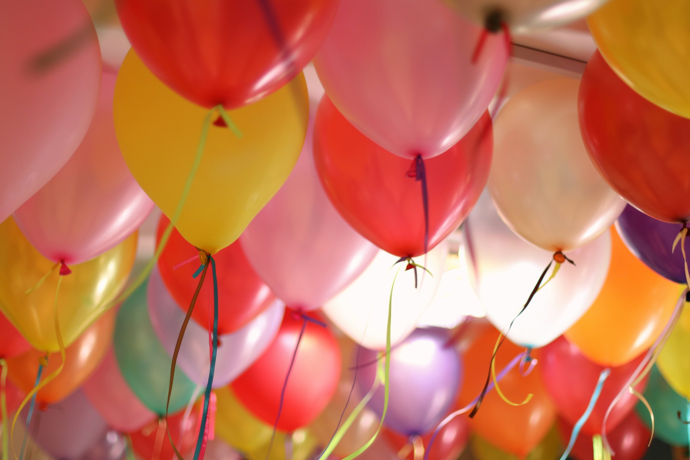 Viele bunte Luftballons mit Schnüren daran.